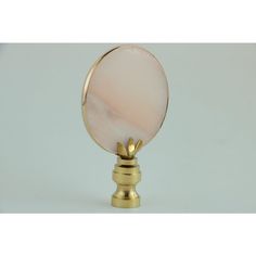 a gold plated metal object with a pink marble on it's top, against a white background