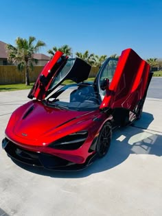 a red sports car with its doors open in a parking lot next to palm trees