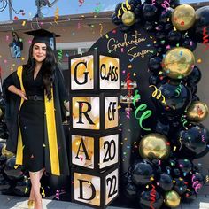 a woman standing in front of a graduation sign