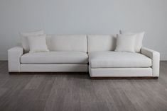 a white couch sitting on top of a hard wood floor next to a gray wall