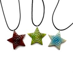 three star shaped pendants with spiral designs on them, one is green and the other is red