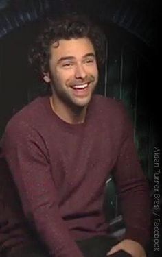 a man sitting down smiling at the camera