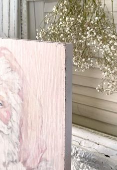 a painting of santa claus on a wood paneled wall next to a vase with white flowers