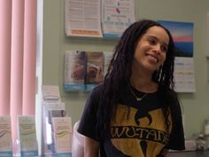 a woman with long black hair standing in front of a counter and smiling at the camera