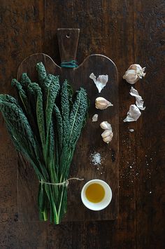 an assortment of vegetables on a cutting board next to garlic and seasoning flakes