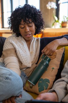 a woman sitting on a couch holding a water bottle