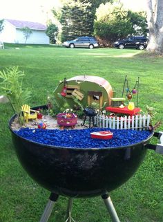 an outdoor bbq with blue gravel in the middle and toys sitting on it's side