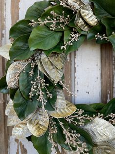 a close up of a wreath with leaves and flowers hanging on a wooden door frame