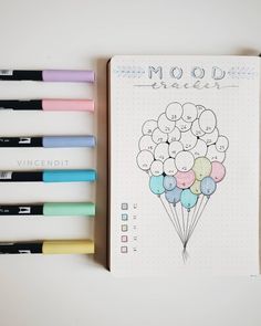 a notebook with some markers and pens next to it