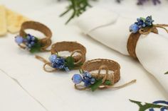 napkin rings with blue flowers on them are sitting on a white table cloth next to other napkins