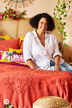 a woman sitting on top of a bed next to a wicker basket filled with flowers