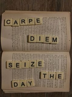 two scrabbled letters spelling the word carpe diem on top of an open book