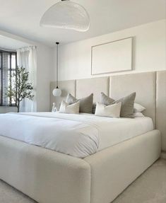 a large white bed sitting in a bedroom next to a window