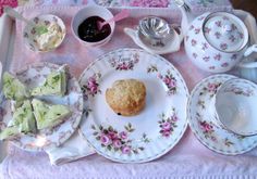 an assortment of teas and pastries on a pink tablecloth with floral designs