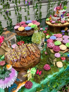 an assortment of cupcakes and pastries are displayed on a table with moss