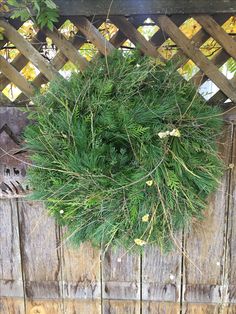 a green wreath hanging from the side of a wooden fence