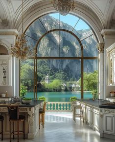 a large kitchen with an arched window overlooking a lake and mountains is pictured in this image