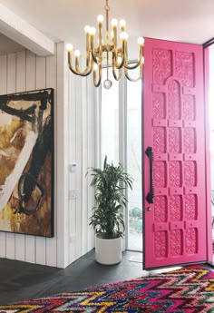 a pink door is in the middle of a room with a rug and potted plant