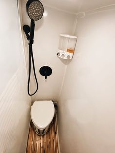 a white toilet sitting in a bathroom next to a shower head