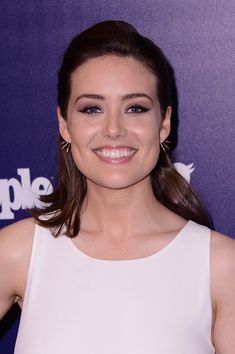 a woman in a white dress smiling at the camera