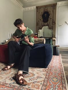 a young man sitting on top of a blue couch holding a guitar in his hands