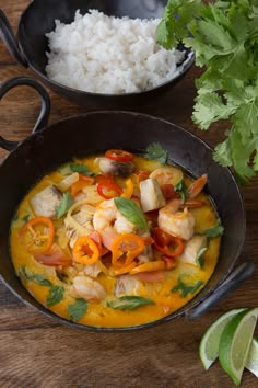 some food is in a black bowl on a table with rice and cilantro