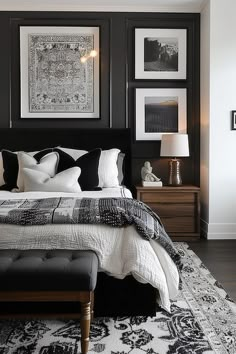 a black and white bedroom with pictures on the wall above the bed, along with an ottoman