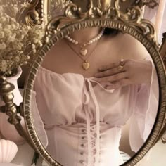 a woman in a white corset looking into a mirror