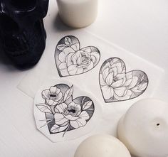 three heart shaped stickers sitting on top of a table next to an egg shell