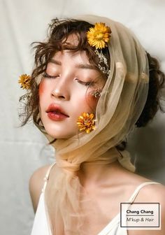 a woman with flowers in her hair and veil over her head is looking at the camera