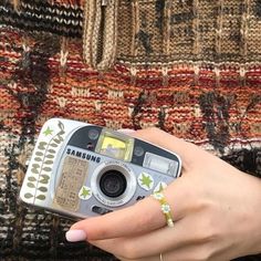 a woman holding a camera in her right hand and wearing a ring on her left