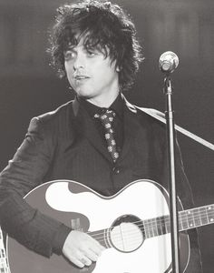 a man holding a guitar in front of a microphone