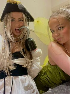 two women dressed in costumes posing for the camera with one holding a blow dryer