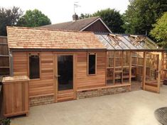 a small wooden building sitting in the middle of a yard with lots of windows and doors