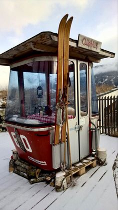 a red and white bus with skis on it's roof in the snow