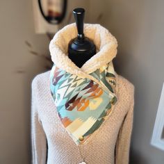 a white sweater with a multicolored scarf around it's neck and a black mannequin