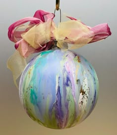 a glass ornament hanging from a hook on a string with ribbon and bow