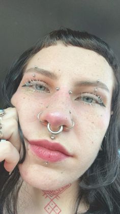 a woman with piercings on her nose and nose ring in front of her face