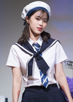 a young woman wearing a sailor outfit and holding a teddy bear in her lapel