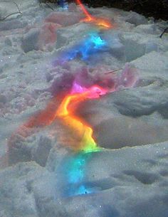 a rainbow colored stream of water in the snow with text that reads, christmas lights under the snow or hell having a party?