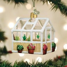 an ornament hanging from a christmas tree with potted plants in front of it