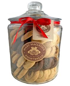 a jar full of cookies with a red ribbon around it's top and label on the lid