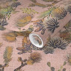 a close up view of a fabric with flowers and leaves on the ground, in neutral colors