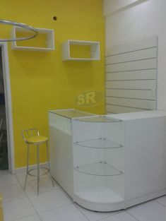 an empty room with yellow walls and white counter top in the center, next to a chair