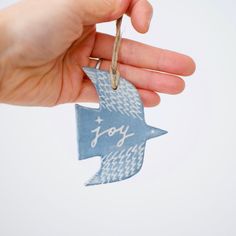 a hand holding a blue ornament with the word joy on it and an arrow