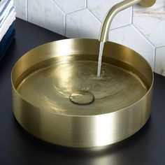 a gold sink with a faucet running from it's spout in a bathroom