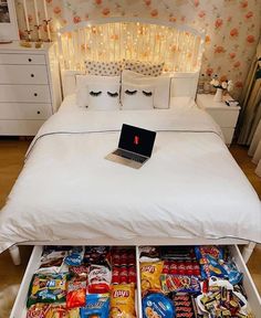 an open laptop computer sitting on top of a bed with lots of food in it