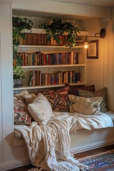 a room with bookshelves filled with lots of books and pillows on the floor