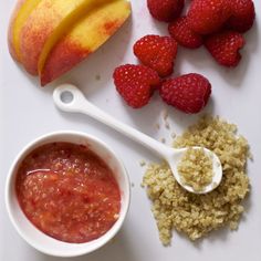 an apple, strawberries, oatmeal and fruit on a white surface