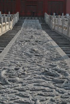 a long stone path with many heads on each side